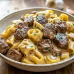 Close-up of seared Garlic Steak and cheesy Tortellini coated in creamy sauce, steaming in a cast-iron Skillet — ideal for cozy Weeknight Meals.