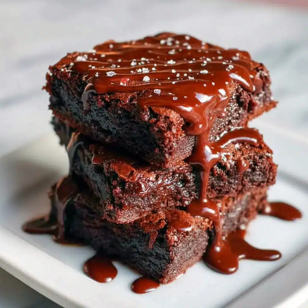 Fudgy Greek Yogurt Brownies stacked on a plate, glossy dark centers and a few sprinkled chocolate chips for a rich, healthier treat.