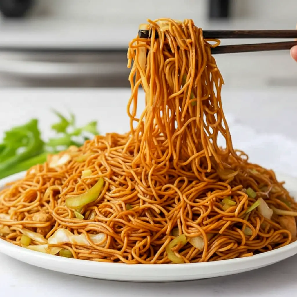 Close-up of Homemade Panda Express Chow Mein in a skillet: glossy chow mein noodles with shredded cabbage, sliced celery, and onions.