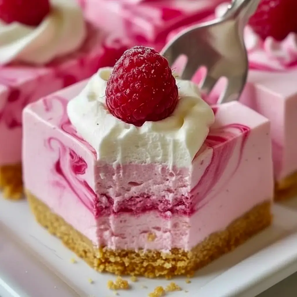 Close-up of a chilled slice of No-Bake Raspberry Swirl Cheesecake with vivid raspberry ribbons and a buttery graham crust — a tempting Raspberry No Bake Dessert for spring gatherings.