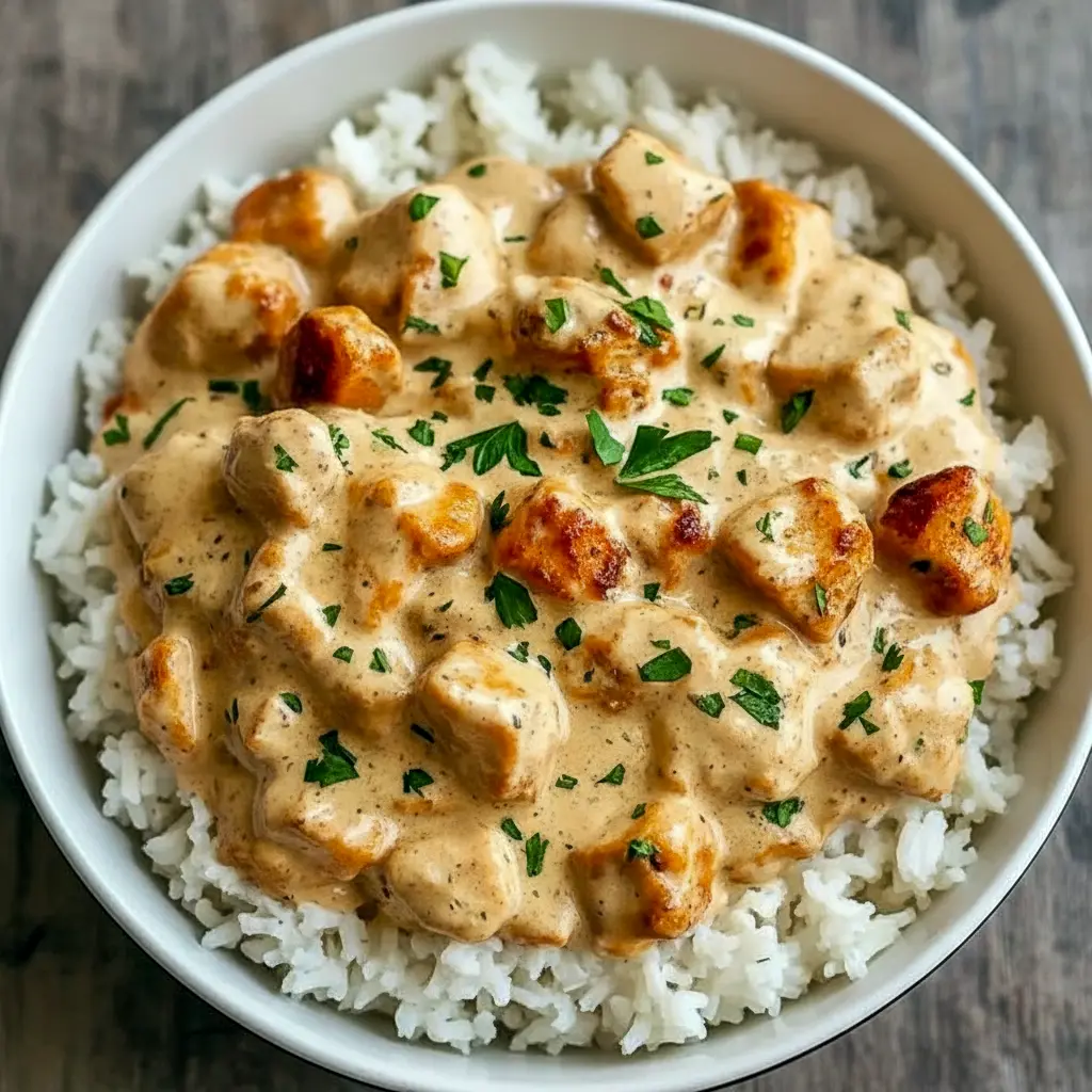 Skillet of golden Chicken Dinner Recipes—seared chicken breasts smothered in cheesy sauce, served atop white rice and garnished with parsley (perfect Fast Dinners idea).