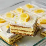 Slice of No-bake Lemon Dessert with creamy lemon pudding layers, softened graham crackers, whipped topping, and a sprinkle of lemon zest.