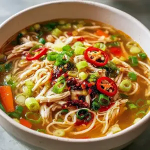 Ginger Scallion Chicken Noodle Soup — steaming bowl with shredded chicken, scallions, noodles, and carrot matchsticks, finished with a soy-vinegar drizzle and chili oil.