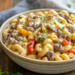 Golden skillet of Philly Cheesesteak Mac & Cheese with melted cheese, peppers, and beef — perfect for Easy Family Meal Prep.