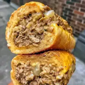 How To Make Philly Cheesesteak Sloppy Joes — close-up of melty provolone, seasoned ground beef, caramelized onions and bell peppers piled on a toasted brioche bun.