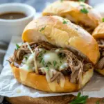 Crockpot French Dip Sandwiches served on toasted hoagie rolls with melted cheese and a bowl of au jus, perfect for Dinner Recipes Weeknight comfort food.
