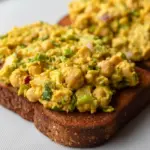 Bowl of Curried Chickpea Salad with a creamy curry dressing, celery, red onion, and herbs, styled as a Vegetarian Recipes Sandwich filling for a healthy lunch.