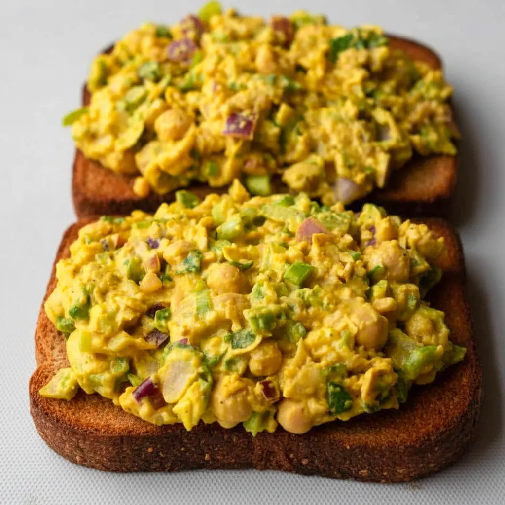 Bowl of Curried Chickpea Salad with a creamy curry dressing, celery, red onion, and herbs, styled as a Vegetarian Recipes Sandwich filling for a healthy lunch.