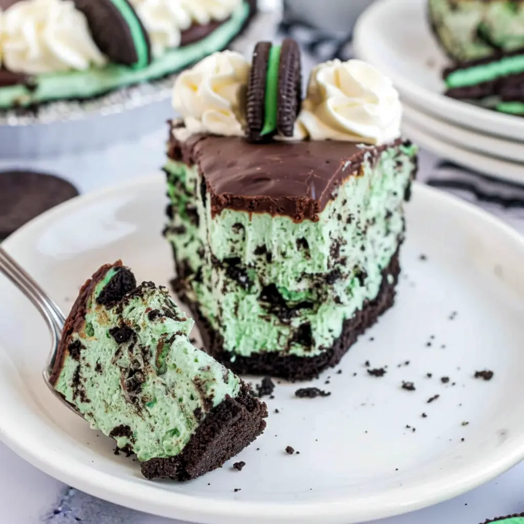 A creamy green slice of Grasshopper Pie with chocolate crumbs and whipped topping, creating a beautiful Chocolate Grasshopper Pie for any occasion.