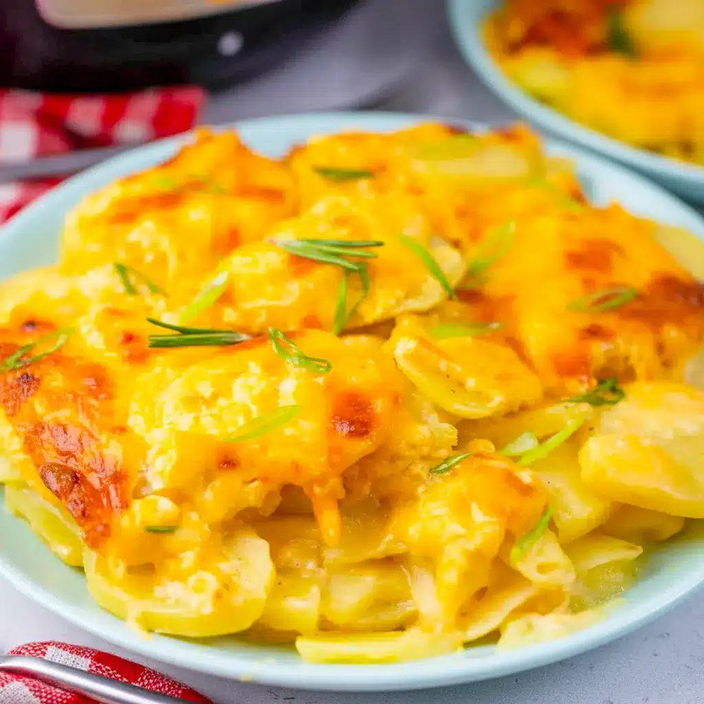 A dish of Instant Pot Scalloped Potatoes with a golden bubbly cheese topping, creamy sliced potatoes, and a rich baked finish for a classic comfort-food side.