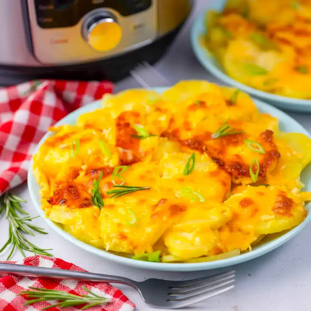 A dish of Instant Pot Scalloped Potatoes with a golden bubbly cheese topping, creamy sliced potatoes, and a rich baked finish for a classic comfort-food side.