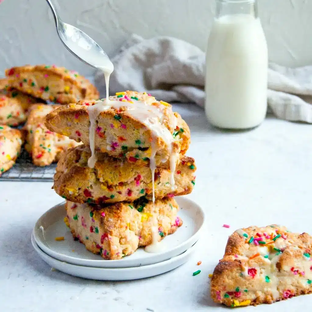 Birthday Cake Scones stacked on a platter with icing and sprinkles, a bakery-style choice for Best Baked Desserts.