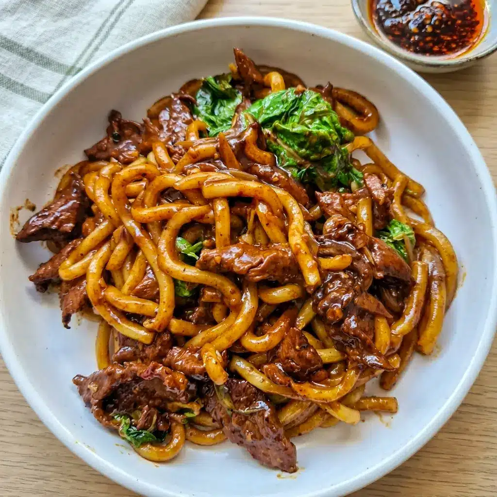 Black Pepper Beef Udon in a skillet with onions and greens, a comforting Asian Dishes recipe that comes together quickly.