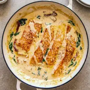 Tuscan Salmon with Parmesan Cream Sauce served in a skillet with spinach and sun-dried tomatoes, styled as an easy Entree Ideas Dinner.
