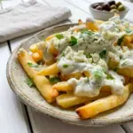 Greek Fries with Feta Cheese piled high with crispy potatoes and a creamy Greek Feta Cheese Recipes style topping.