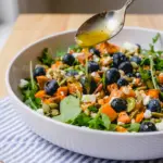 A bright and colorful Honey Sweet Potato Summer Salad topped with blueberries, goat cheese, and roasted sweet potatoes for Healthy Meals For A Crowd.