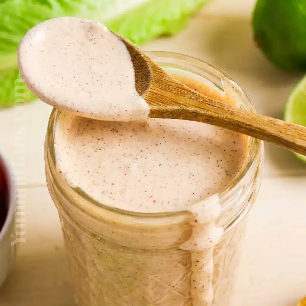 Taco Salad Dressing shown in a mason jar next to a salad bowl, inspired by Southwest Taco Salad Dressing flavor and fresh ingredients.