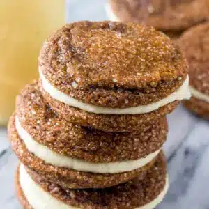 Ginger Molasses Sandwich Cookies with Eggnog Frosting stacked on a holiday plate, a festive take on Molasses Sandwich Cookies with soft, chewy layers.