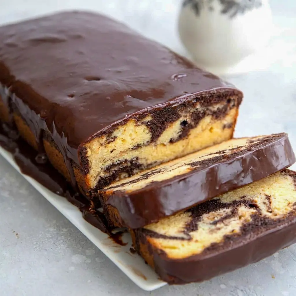 Close-up of glossy glaze dripping down Keto Marble Pound Cake, finished with a silky Keto chocolate glaze.