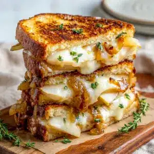 Golden, melty Pear & Apple Grilled Cheese With Caramelized Onions sliced in half, full of fall food inspiration.