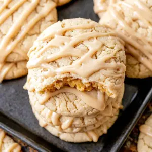 Soft Maple Sugar Cookies stacked high and drizzled with icing, a cozy batch of homemade Maple Syrup Cookies ready to serve.